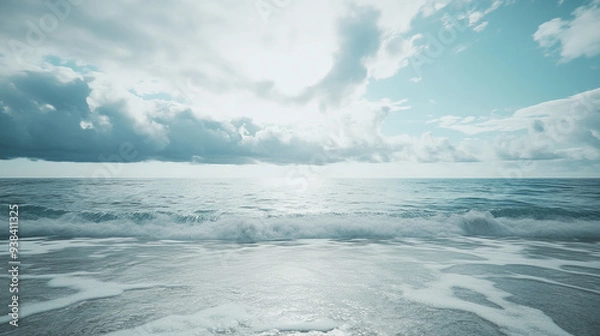 Fototapeta Calm ocean waves roll gently beneath a cloudy sky, offering a serene seascape.