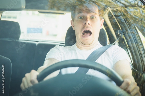 Obraz Junger Mann sitzt im Auto und ist schockiert