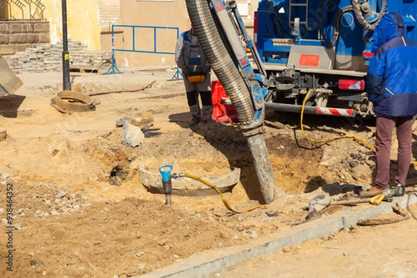 Obraz Workers use a suction excavator based on a truck to sample soil in a well for communications