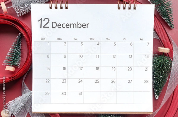 Fototapeta December 2024 calendar schedule , Top view shot featuring calendar with December month, little Christmas tree, glitter silver ribbon and red ribbon on red background. Chrismas and New year concept.