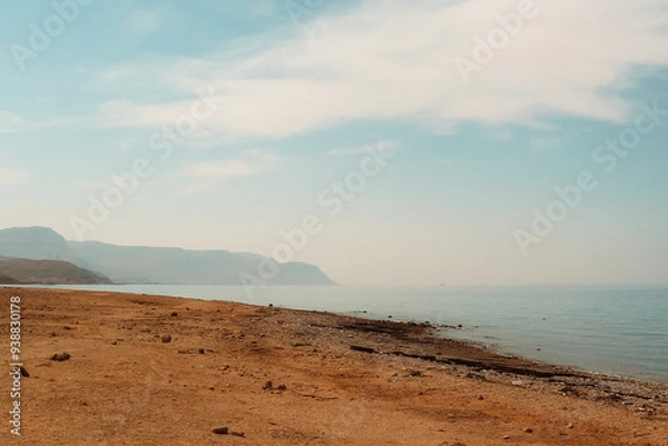 Fototapeta Daytime view of Al Ain Al Sokhna beach, Suez, Egypt. The calm shoreline stretches with mountains in the distance under a clear sky.