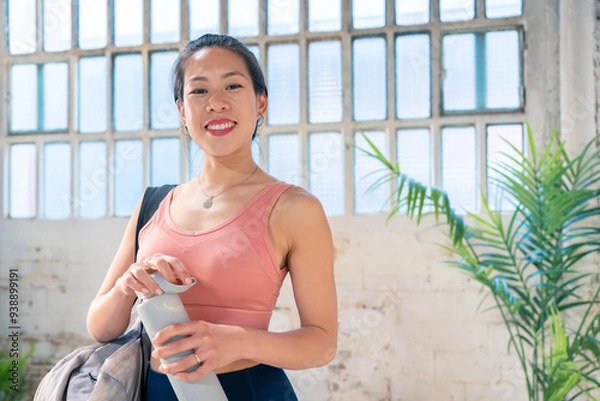 Fototapeta Sporty asian woman with a bottle of water in the gym. Healthy lifestyle concept. High quality photo