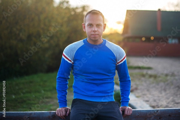 Obraz Attractive man stands on  beach in the evening sunset after sport