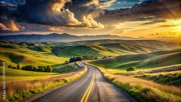 Fototapeta Serene landscape of a winding road disappearing into the horizon, surrounded by rolling hills and vast open spaces, evoking a sense of freedom and adventure.