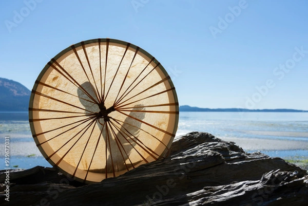 Fototapeta A silhouette image of a handmade leather meditation drum with ocean background. 