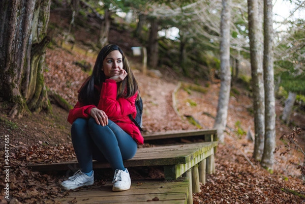 Fototapeta Pretty woman sitting in forest and smiling after hking. Thoughtful and reflexive expression.