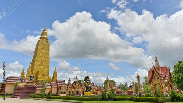 Fototapeta Panoramic view of stunning exterior architecture in buddhist temple with golden pagoda under cloudy blue sky. Wat Mahathat Wachiramongkhon or Wat Bang Thong, Krabi Province, Thailand.