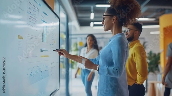 Obraz 6. A group of office workers collaborating on a digital whiteboard in a bright, open workspace