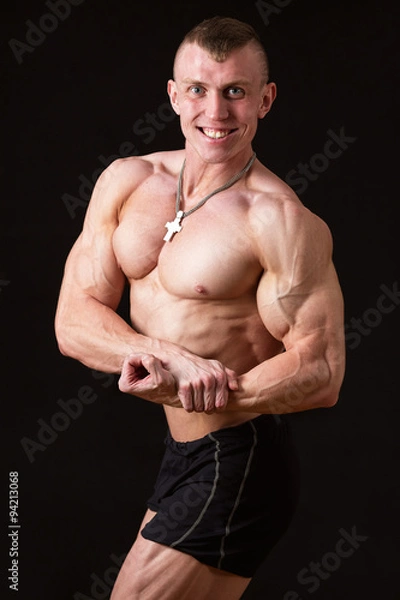 Fototapeta smiling  muscular man on a black background in the studio