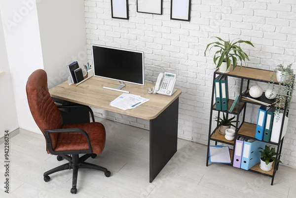 Fototapeta Interior of stylish office with workplace, armchair, modern computer and shelving unit