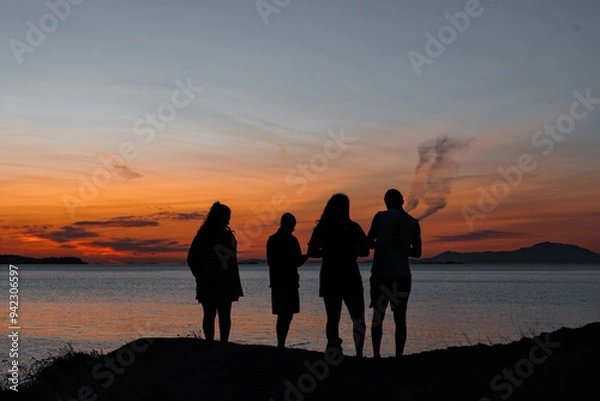 Fototapeta silhouette of 4 people at the shoreline at sunset