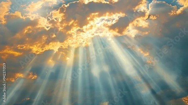 Fototapeta Sunbeams filter through gaps in the clouds, creating radiant shafts of light in the sky.