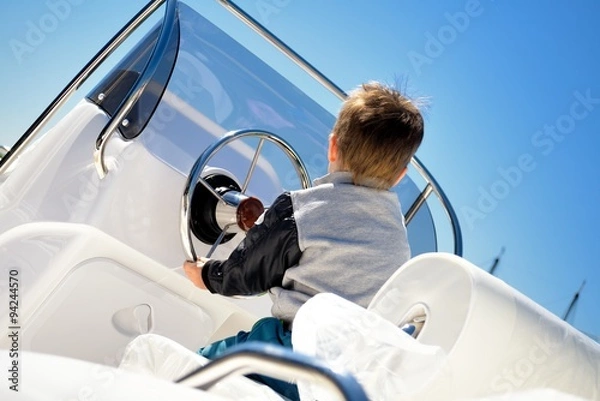 Obraz Little child sailor steering a sailboat as captain