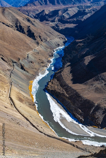 Fototapeta Indus river half frozen with clear water and mountain ranges on both sides.
