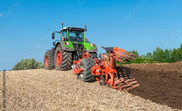 Fototapeta Tractor with 7-share reversible plow cultivating the field after the grain harvest - 2184