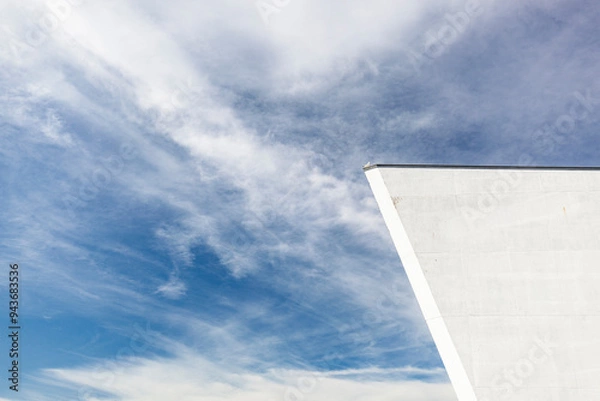 Fototapeta Detail eines Gebäude mit weißer Betonwand. Architektur vor Himmel im Hintergrund.
Detail of a building with white concrete wall. Architecture against the sky in the background.