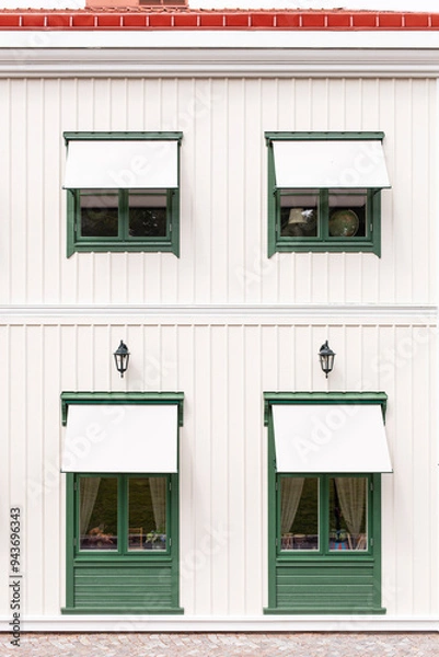 Fototapeta Grüne Fenster vor weißer Holzfassade. Skandinavische Architektur. Green windows in front of a white wooden façade. Scandinavian architecture.