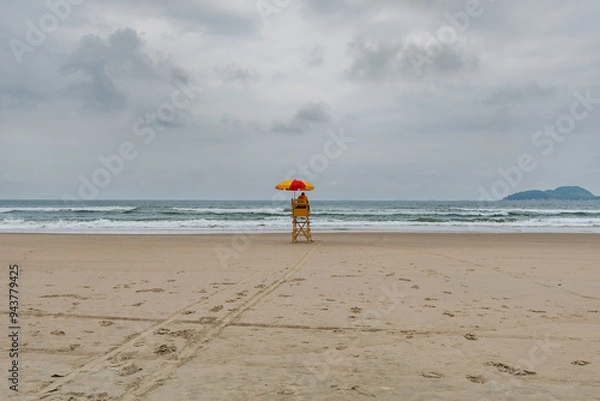 Fototapeta Beach lifeguard in the middle of the beach on a cloudy day and no people on the sea. Tombo beach, Guaruja - SP, Brazil.