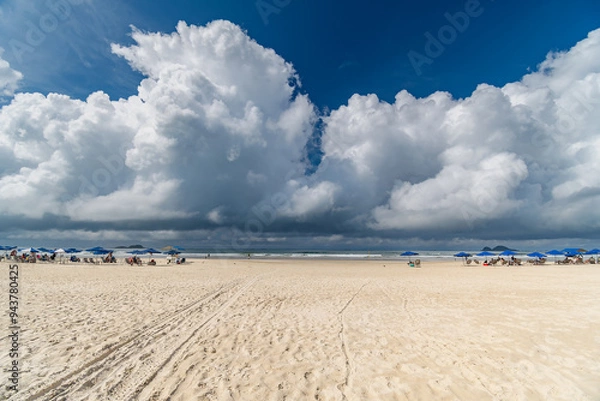 Fototapeta Morning at Enseada Beach on a beautiful sunny day with some rain clouds around, view of the beach sand and the sea. Guaruja - SP, Brazil.