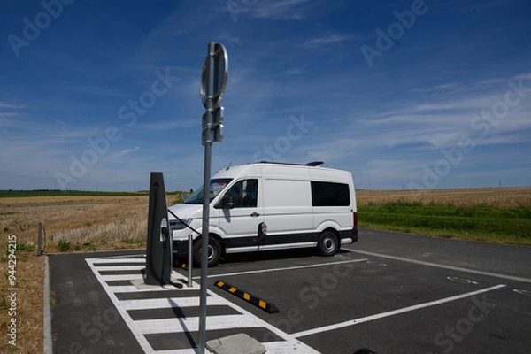 Obraz An electric van is charging at a charge station in the middle of the fields and in the middle of nowhere.