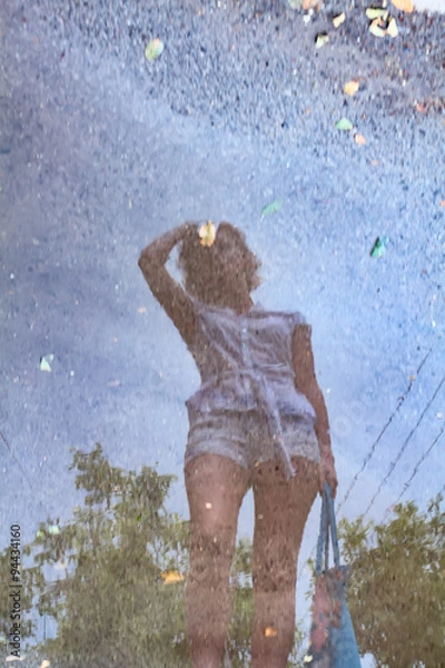 Obraz a reflection of a young girl in a puddle after rain.
