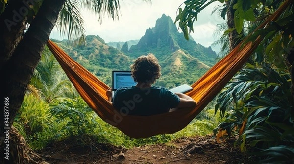 Fototapeta Person relaxing in a hammock with a laptop, overlooking a tropical mountain landscape.