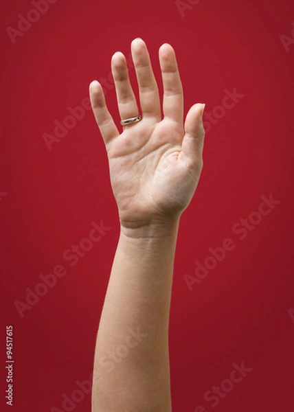 Obraz  Raised Female Hand Wearing Ring Isolated on Red
