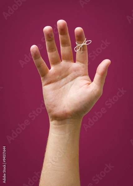 Obraz Hand with remider string isolated on red purple plum background