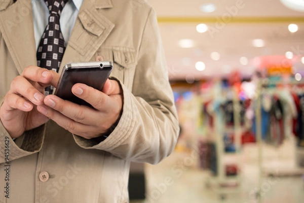 Fototapeta Man in shopping mall using mobile phone.