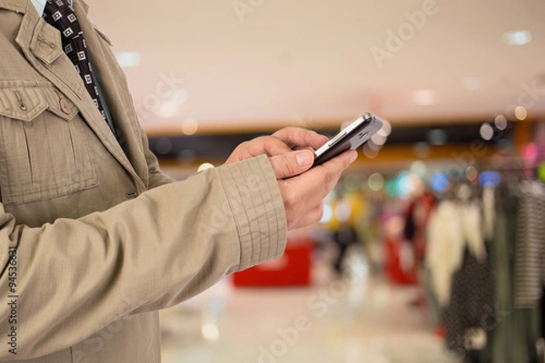 Fototapeta Man in shopping mall using mobile phone.