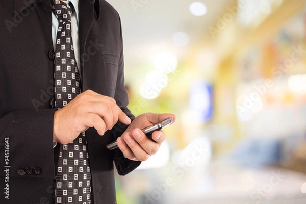 Fototapeta Man in shopping mall using mobile phone.