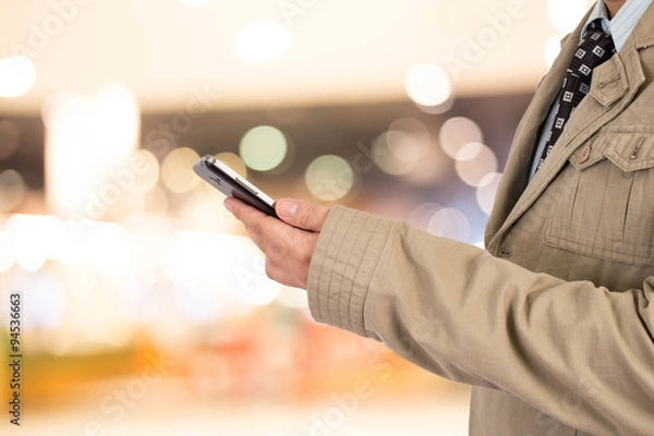 Fototapeta Man in shopping mall using mobile phone.