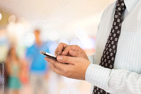 Fototapeta Man in shopping mall using mobile phone.
