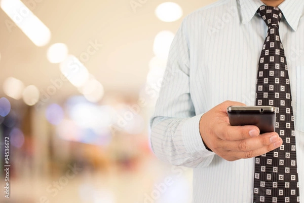 Fototapeta Man in shopping mall using mobile phone.