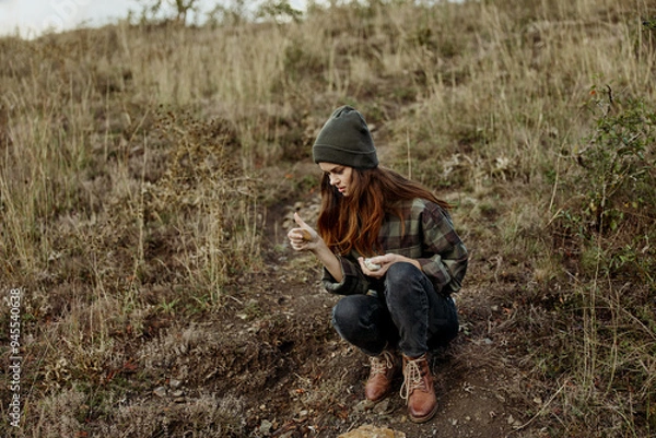 Obraz A stylish woman wearing a beanie and plaid shirt enjoying the breathtaking view from the hilltop during a leisure trip