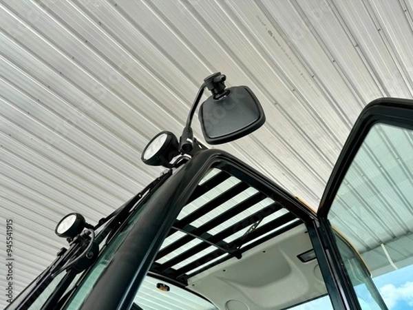 Fototapeta Close-up of a Tractor's Mirror and Cab Roof: A detailed view of a modern tractor's side-view mirror, cab roof, and door, showcasing the sleek design and functionality of agricultural machinery.  
