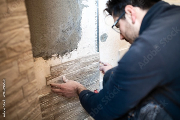 Fototapeta Closeup of a tiler applying tiles to a wall