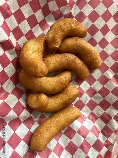 Obraz A baker's dozen fried hush puppies on red and white checkered paper.