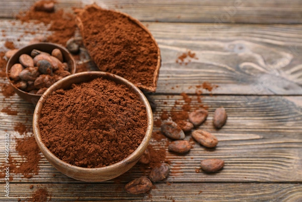 Fototapeta Bowls with cocoa powder and beans on wooden background