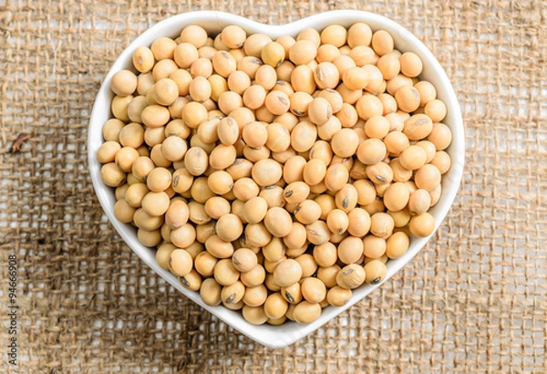 Obraz soybeans in heart ceramic bowl on sackcloth background..