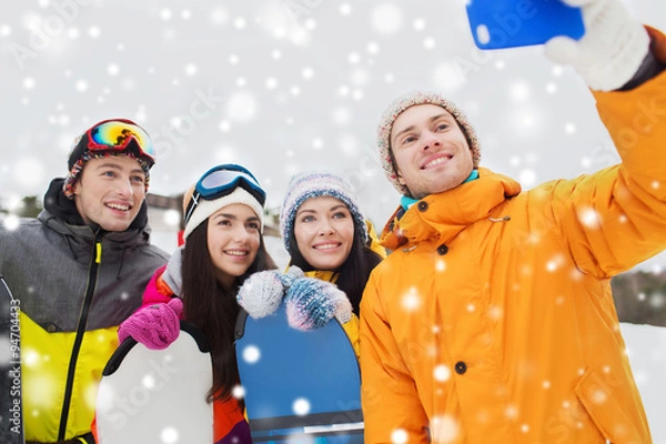 Fototapeta happy friends with snowboards and smartphone