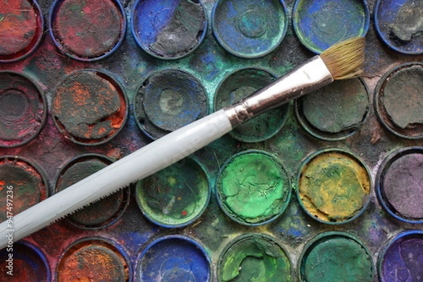 Fototapeta Used paintbrush placed on a set of dirty colorful watercolors in a palette