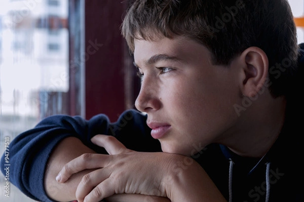 Fototapeta Pensive child looking through a window