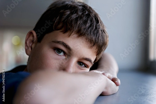 Fototapeta Pensive child looking through a window