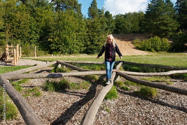 Fototapeta Young girl play in a creative playground in the middle of nature