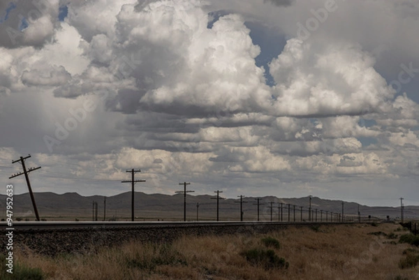 Fototapeta Dramatic clouds over train tracks and telegraph poles