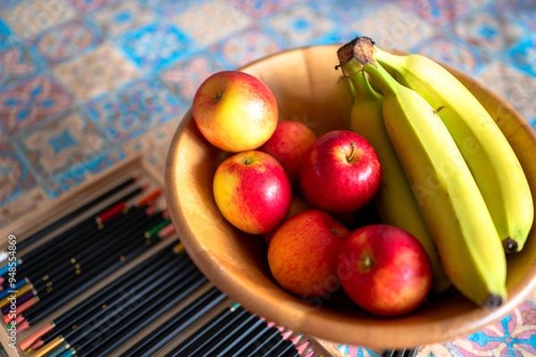 Fototapeta Bowl of apples and bananas on a colourful table setting