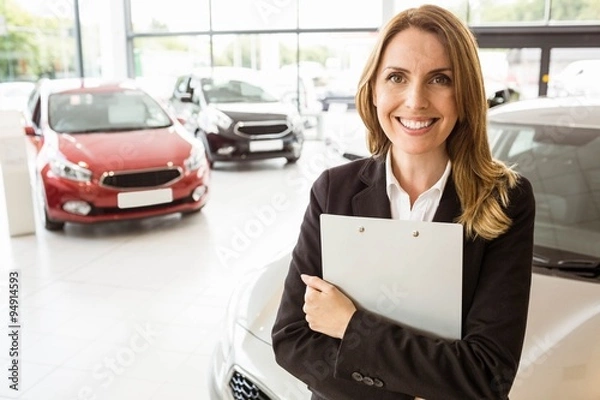 Obraz Smiling saleswoman holding document while looking at camera