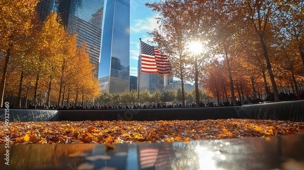 Fototapeta The American flag at Ground Zero standing tall against the backdrop of the Freedom Tower and autumn colors