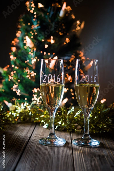 Fototapeta A decorated christmas table with champagne glasses and christmas tree in background. Selective focus.